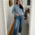 Carly Riordan taking a mirror selfie wearing a blue sweater and jeans.